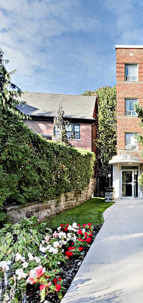 a walkway leading to a brick building with trees and flowers