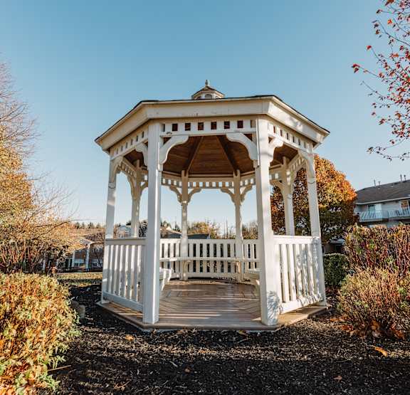 a white gazebo with a wooden deck in a yard