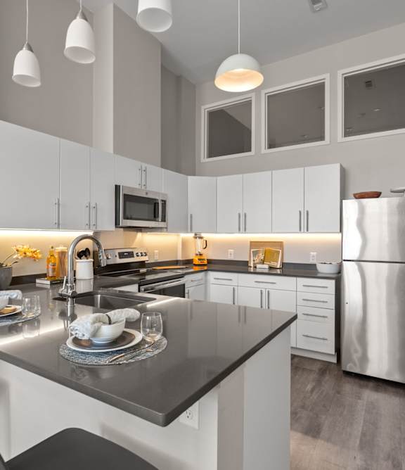 A modern kitchen with a black countertop and stainless steel appliances.