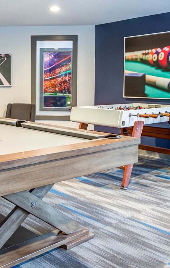 A pool table in a room with a blue wall and a picture of a pool table.