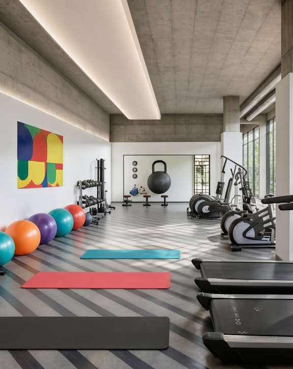 A group of people are exercising in a gym with treadmills and other equipment.