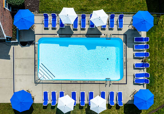 An aerial view of a swimming pool surrounded by blue and white umbrellas.