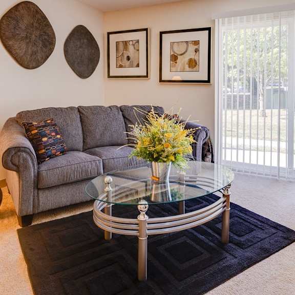 Living room in a Regency Woods model unit, featuring a couch and a glass coffee table.
