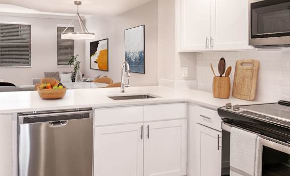 A modern kitchen with white cabinets and stainless steel appliances at Floresta, Jupiter, FL