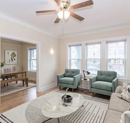 a living room with three windows and a ceiling fan
