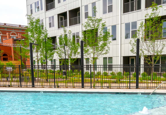a pool with a fence around it and an apartment building in the background