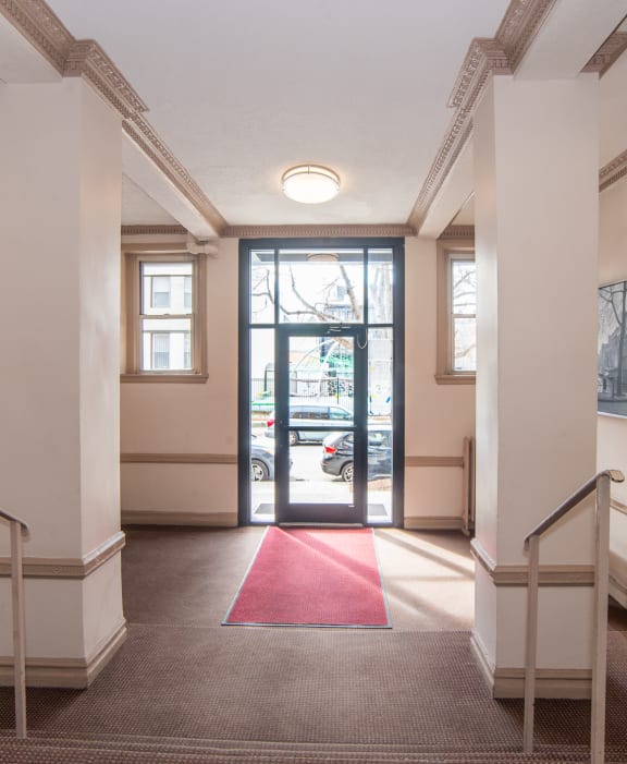 a hallway with stairs and a red carpet in front of a door