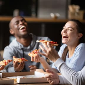 Friends Laughing while Having Pizza Together