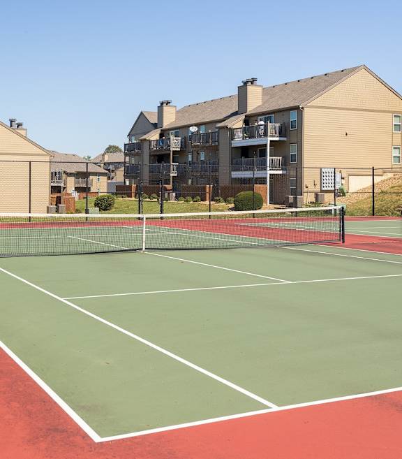 The tennis court at Cedar Crest Apartments, surrounded by open outdoor space and greenery.