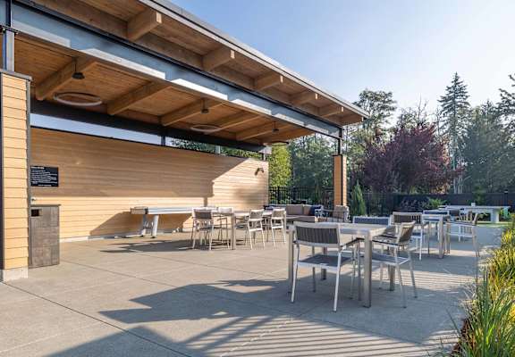 A wooden covered patio with tables and chairs.