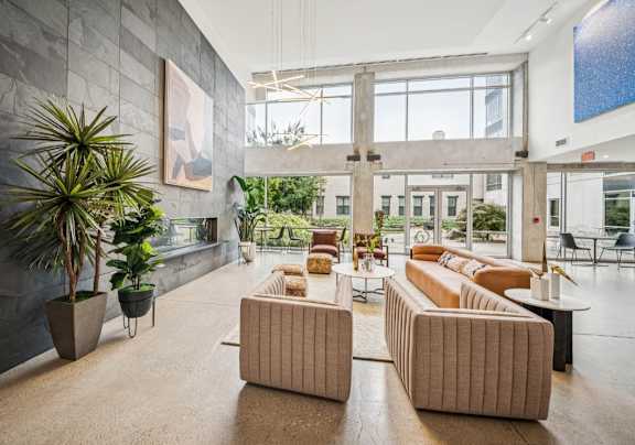 A modern outdoor living space with a white sofa, wooden coffee table, and a hanging chair.