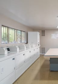an empty kitchen with white cabinets and a table a white room with white washing machines and a table