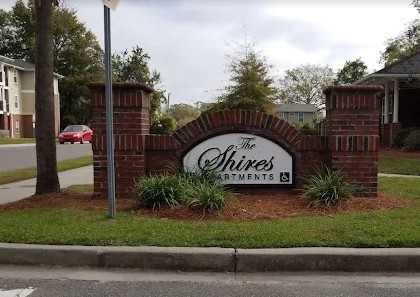 The Shires apartments sign is made of brick and has a green bush in front of it.