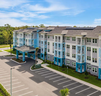 A large blue and white building with a parking lot in front.