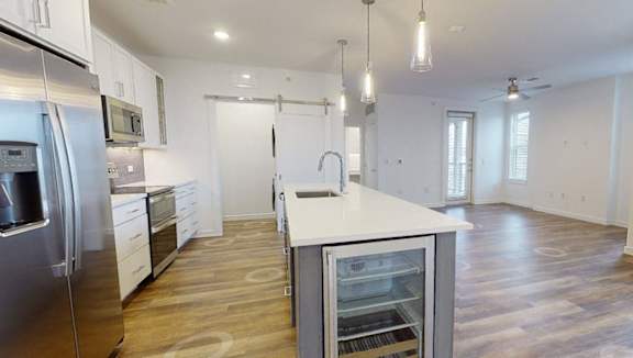A modern kitchen with stainless steel appliances and wooden flooring.