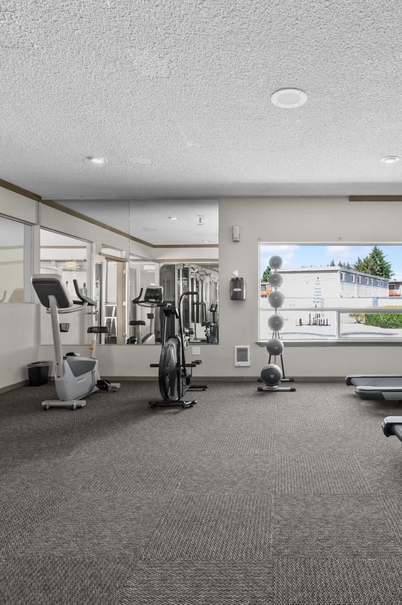 the gym with treadmills and weights at the enclave at university heights apartments