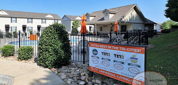 a sign is displayed in front of a white house with a fence and a yard