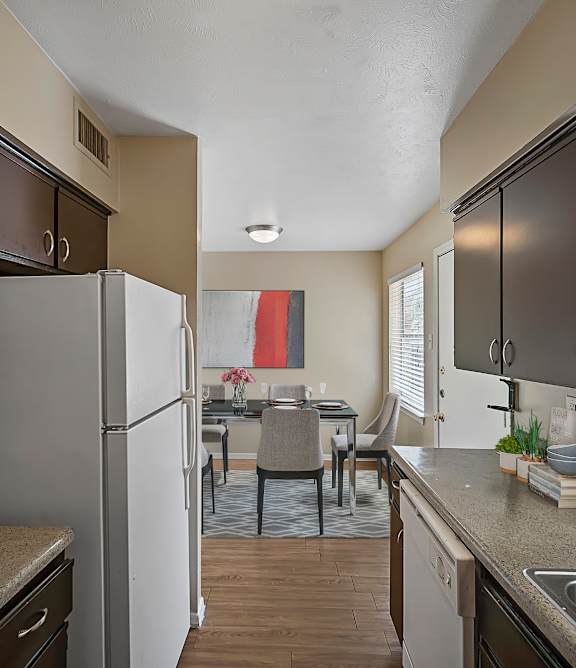 A kitchen with a white refrigerator and black cabinets.