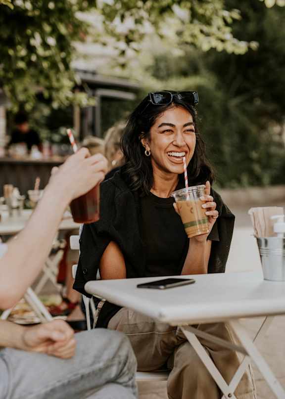 A man and a woman are sitting at a table with drinks, enjoying a conversation.