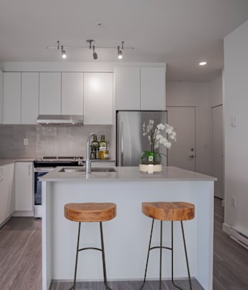 A modern kitchen with white cabinets and a wooden bar stool.