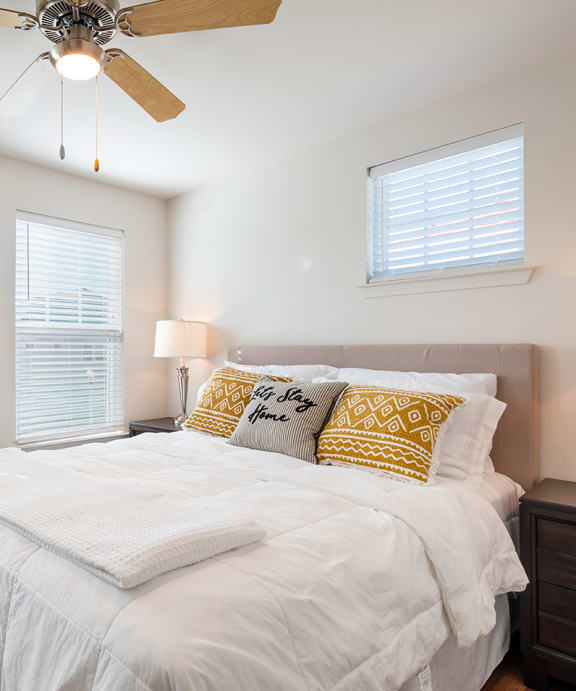a bedroom with a large white bed and a ceiling fan