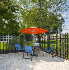 a patio with an orange umbrella and a table and chairs