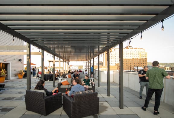 a group of people sitting in chairs under awning on a patio
