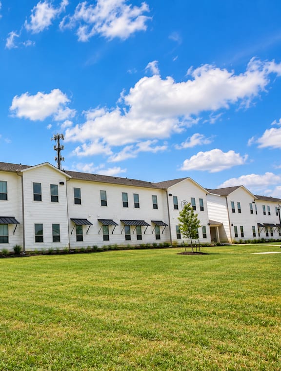 A white building with a green lawn in front and a clear blue sky above.
