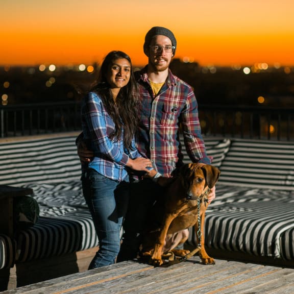 a man and woman standing with their dog on a ledge