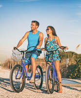 a man and a woman riding bikes on the beach