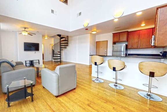 a living room with couches and a kitchen with a staircase