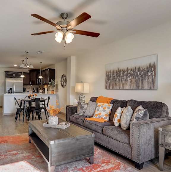 A living room with a grey couch and a ceiling fan.