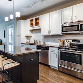 an open kitchen and living room with an island and stools
