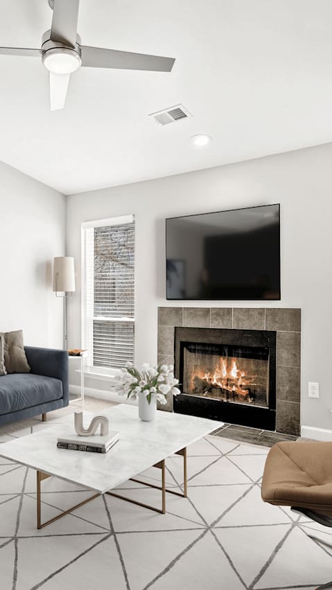 A modern living room with a grey sofa, a coffee table, and a painting on the wall.