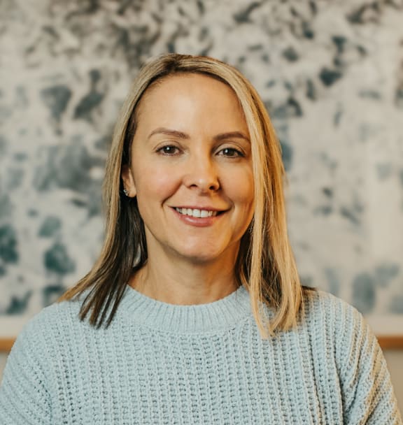 a woman in a blue sweater smiling at the camera