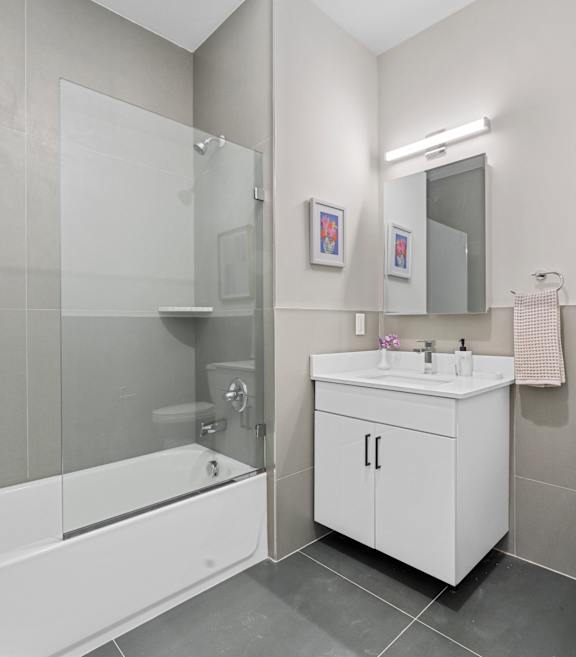 A white bathroom with a toilet, sink, and shower.at 829 Garfield, Jersey City, NJ