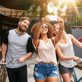 Three friends are riding bicycles and taking a selfie.