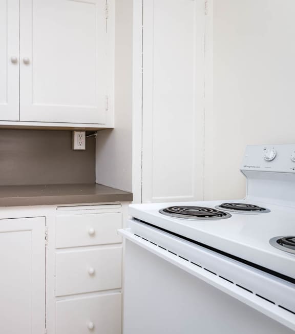 A white kitchen with a stove and cabinets.
