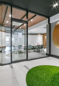 a lobby with chairs and a table in a building with large windows