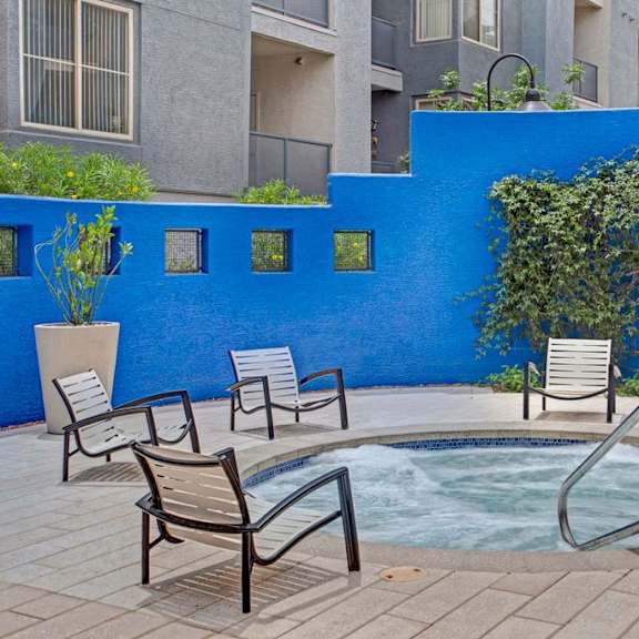 A hot tub outside with a blue wall behind it, surrounded by chairs at Rio Paradiso. 