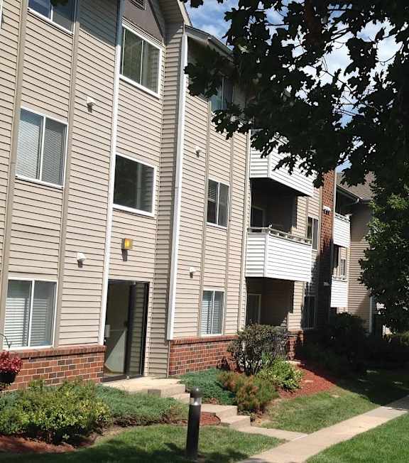Apartment building with a sidewalk and landscaped grounds at Muirfield Apartments in Omaha, NE