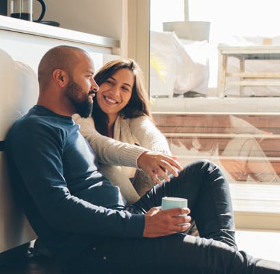 a man and woman sitting on the floor with a cup of coffee