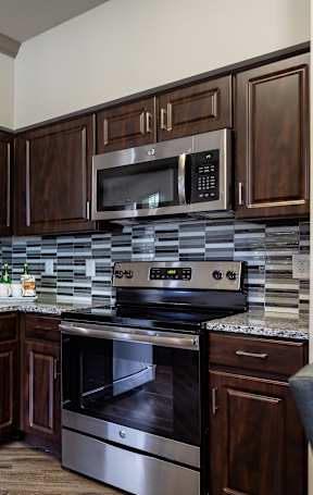 A modern kitchen with dark wood cabinets and stainless steel appliances.