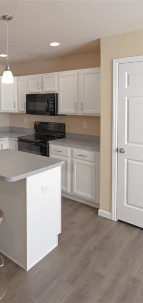 a kitchen with white cabinets and a black stove and refrigerator