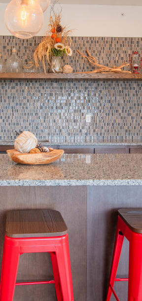 a kitchen with red stools and a granite counter top