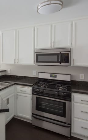 an empty kitchen with white cabinets and black counter tops at Warner Center Townhomes, Canoga Park, CA