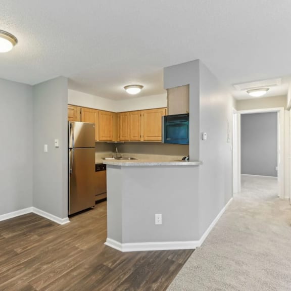 A kitchen area with wooden cabinets and a stainless steel refrigerator.