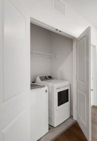 an empty room with large washer and dryer and a wooden floor