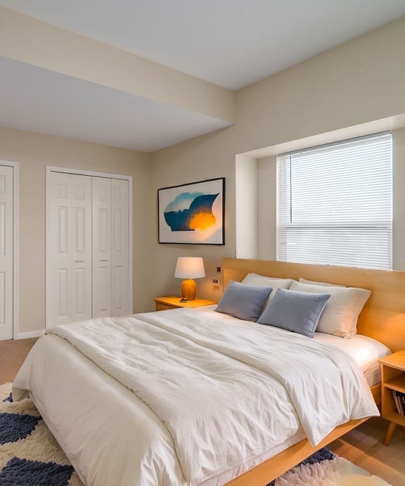 a bedroom with a bed with pillows and two lamps