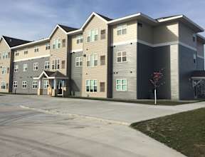 A large apartment complex with multiple buildings and a parking lot in front.